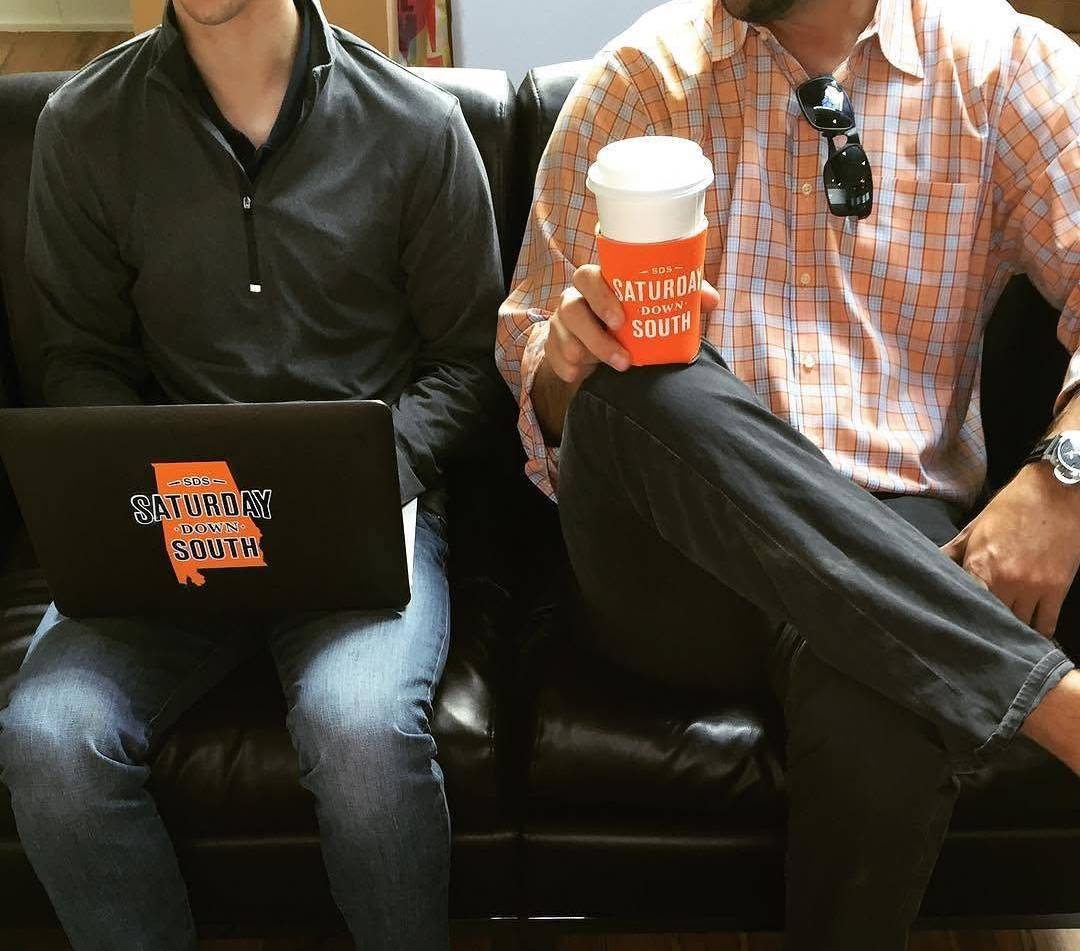 Two members of the Saturday Down South team with a branded laptop and coffee cup
